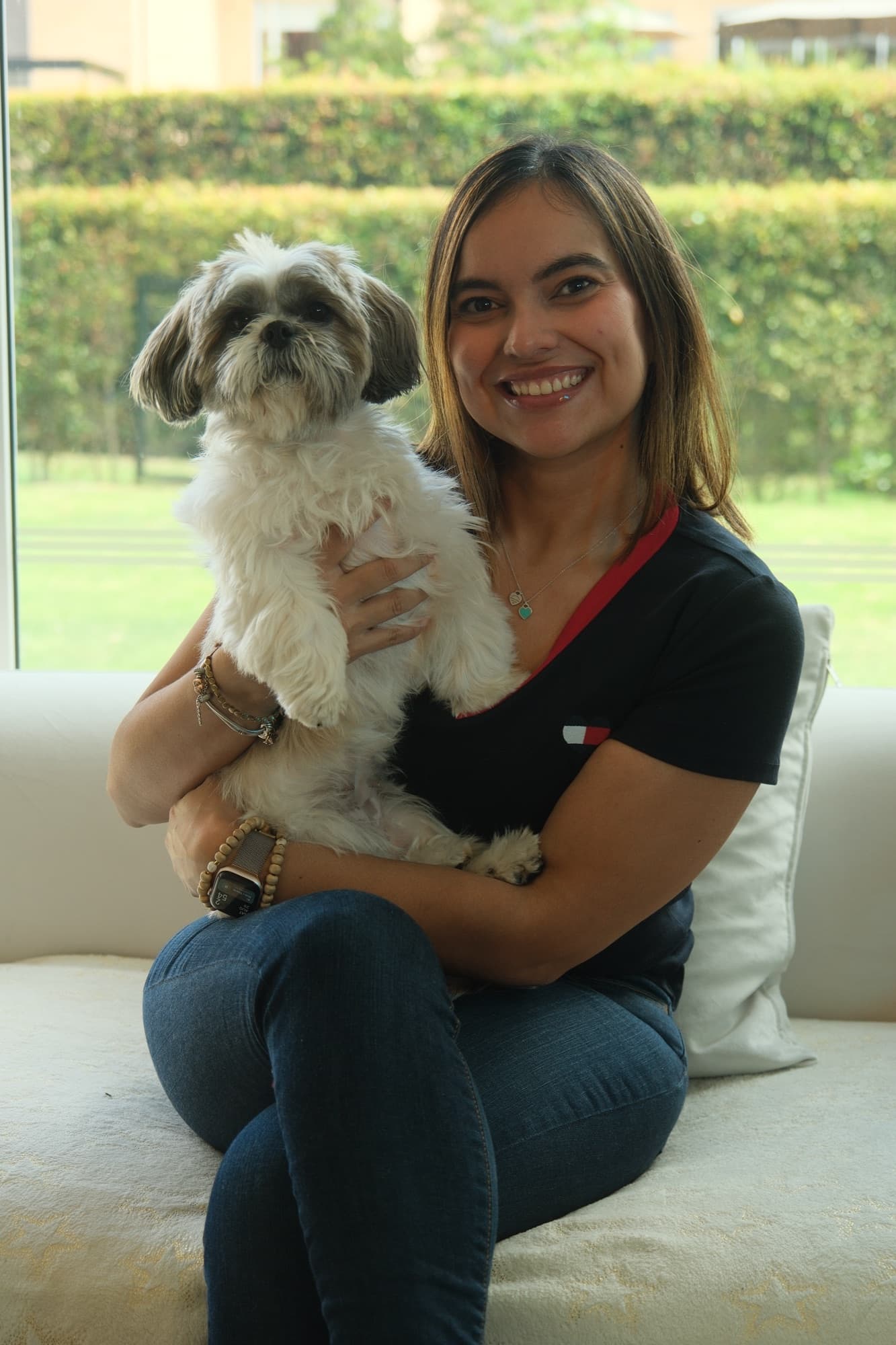 Angélica Cabrera con su perro en brazos, sentada junto a un ventanal.